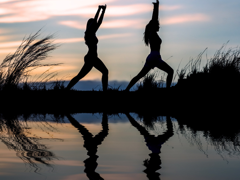 Inner beauty isn’t measured in products — two women practicing yoga at sunset, finding peace and self-care in nature.